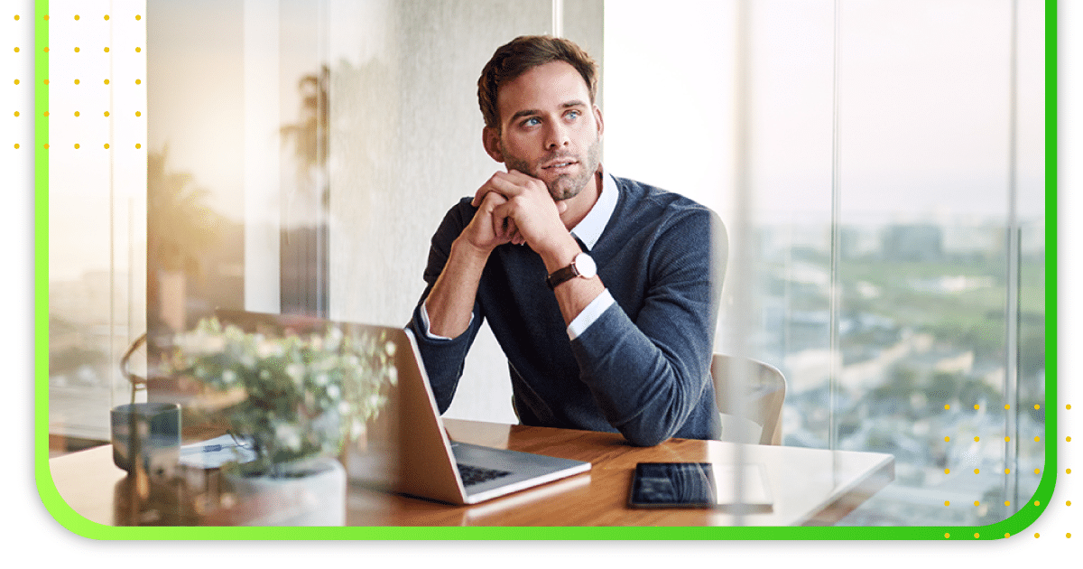 A man sitting at an office, thinking and looking outside